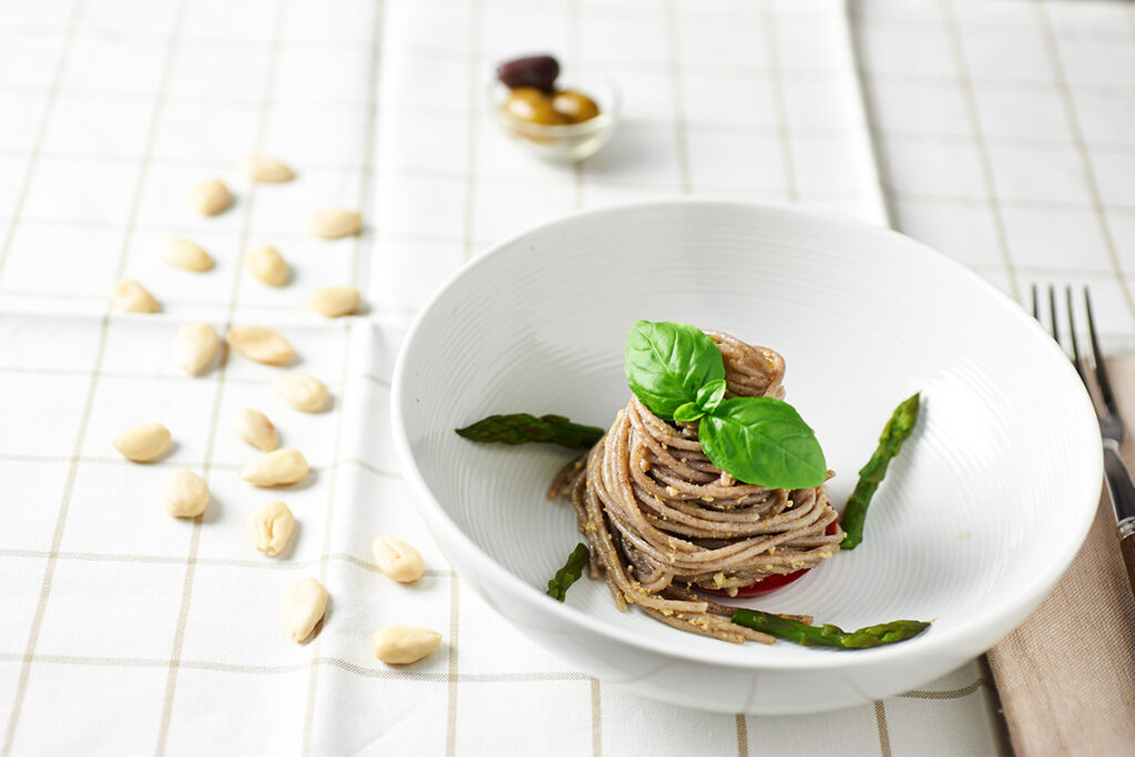 Spaghetti di grano saraceno con pesto di mandorle e olive, asparagi e basilico